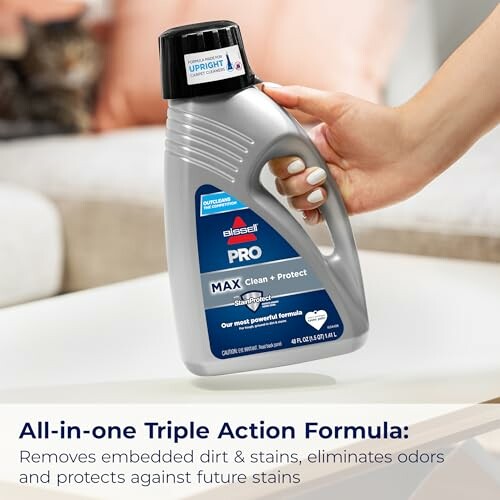 Hand holding a bottle of carpet cleaning solution with triple action formula.