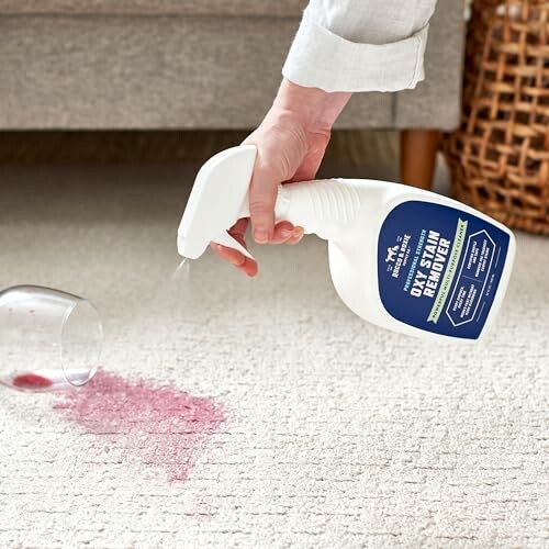 Person using stain remover spray on carpet with red wine spill.