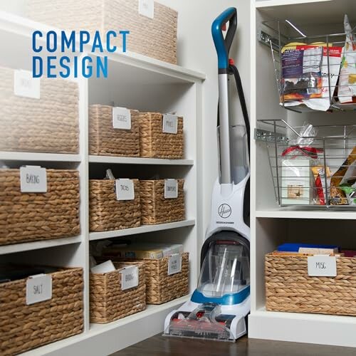 Compact vacuum cleaner stored in a pantry with labeled baskets.