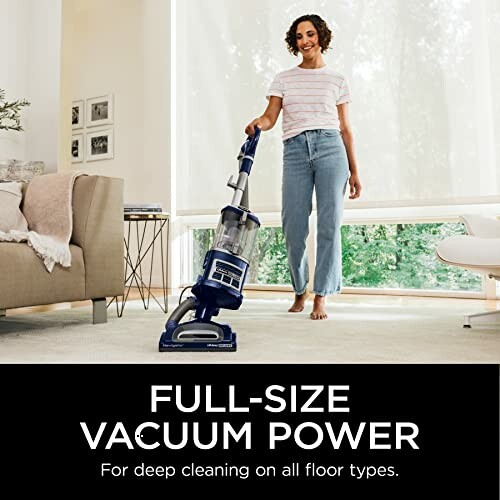 Person using a full-size vacuum cleaner in a living room.