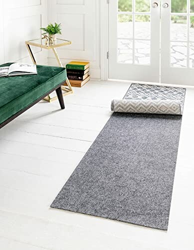 Gray rug partially rolled out in a modern living room with a green bench and side table.