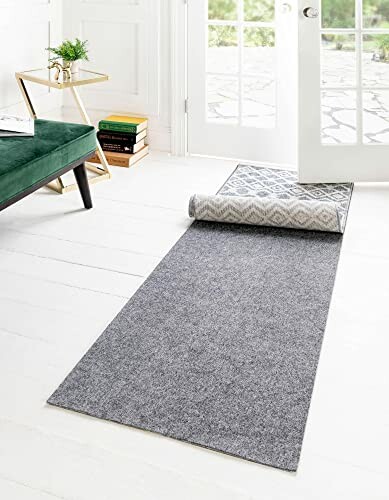 Gray rug partially rolled out on a white floor near a door.