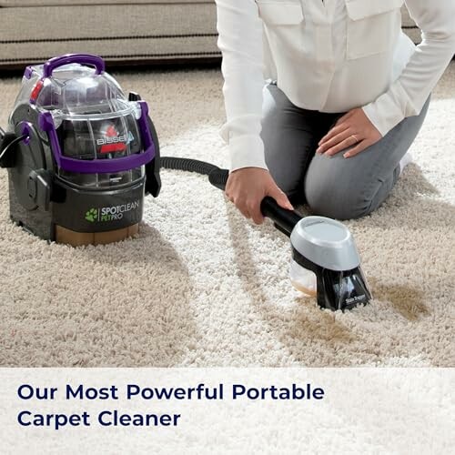 Person using a portable carpet cleaner on a stained carpet.