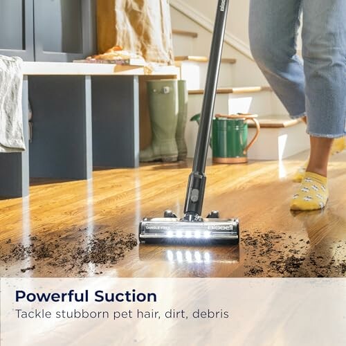 Vacuum cleaner with LED lights cleaning dirt from wooden floor.