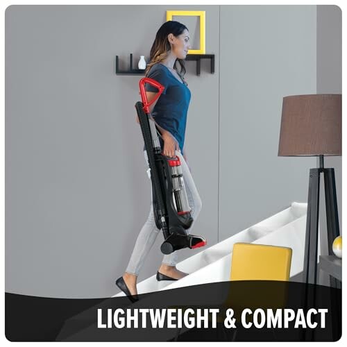 Woman carrying a lightweight and compact vacuum cleaner down the stairs